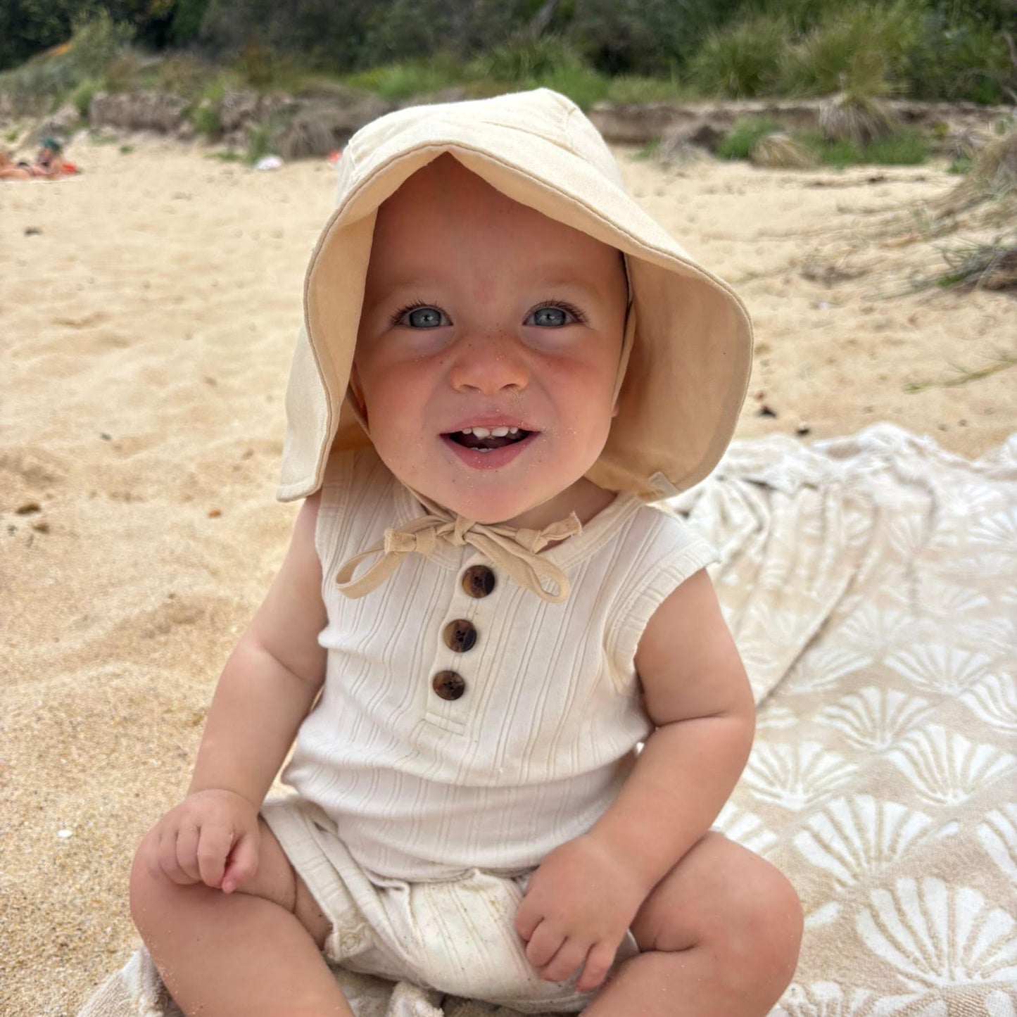 baby enjoying the beach wearing a cotton baby sun hat in beige