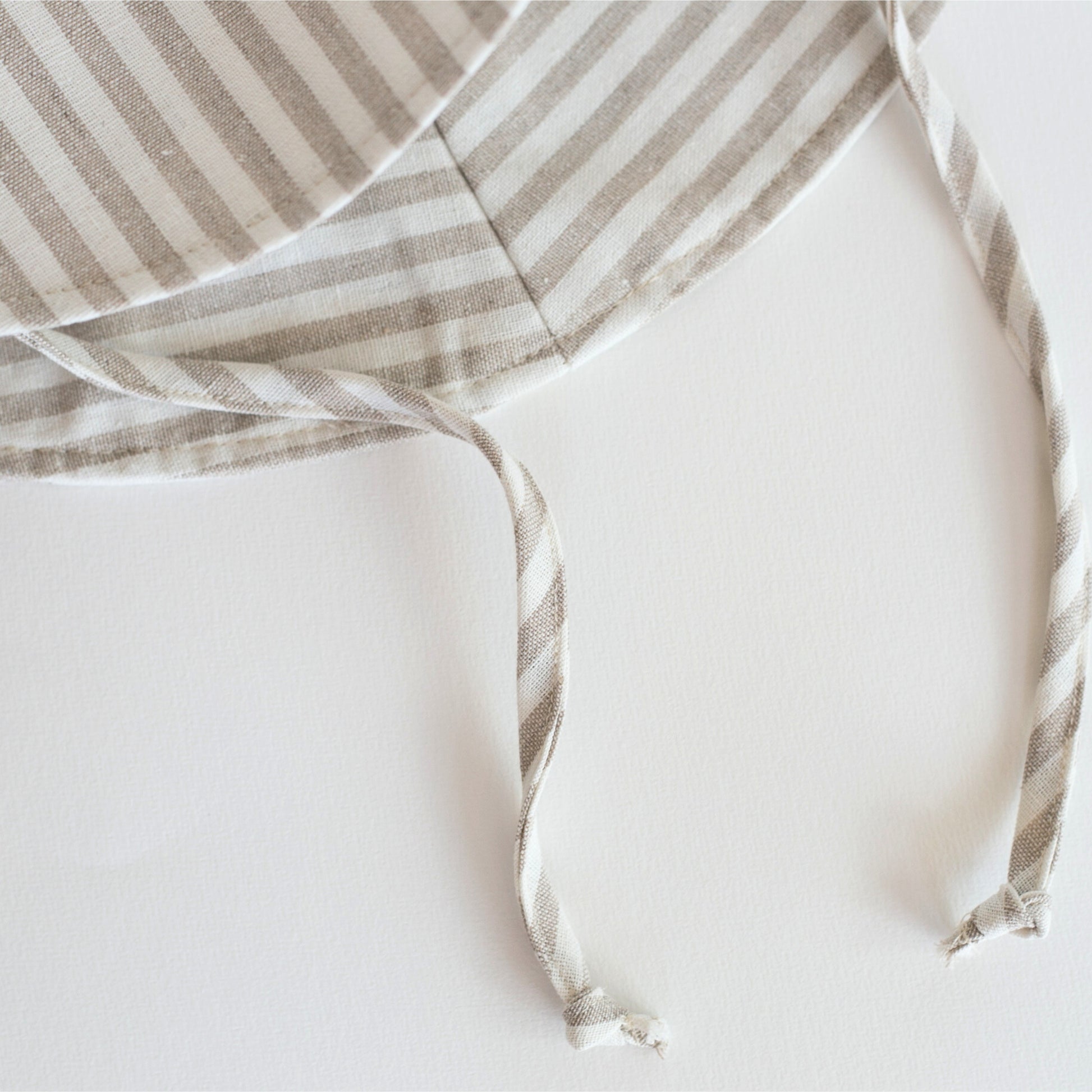 Close-up detail shot of Cloudy Stripes grey stripe baby sun hat, showcasing the breathable cotton fabric, fine stitching, and quality craftsmanship