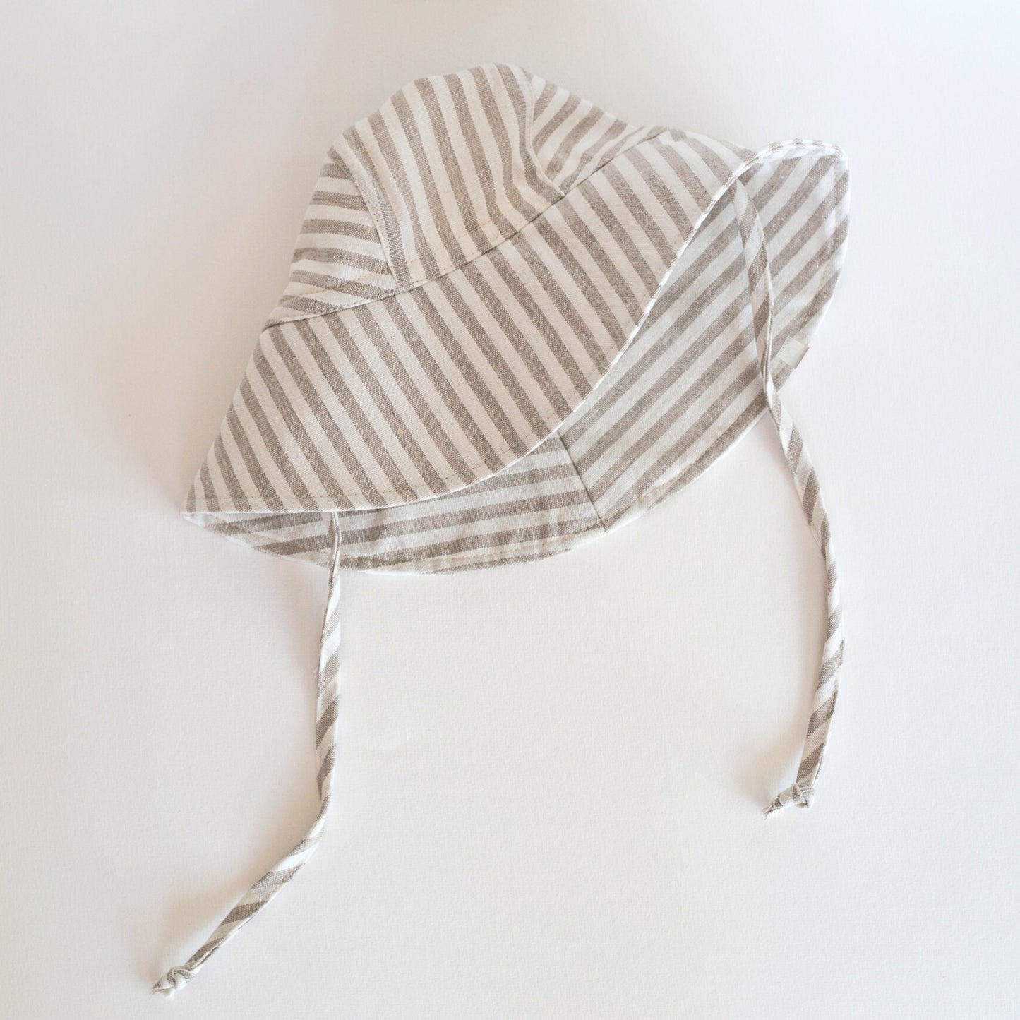 Front view of Cloudy Stripes grey stripe baby sun hat, showcasing the wide brim and stylish striped design made from breathable cotton