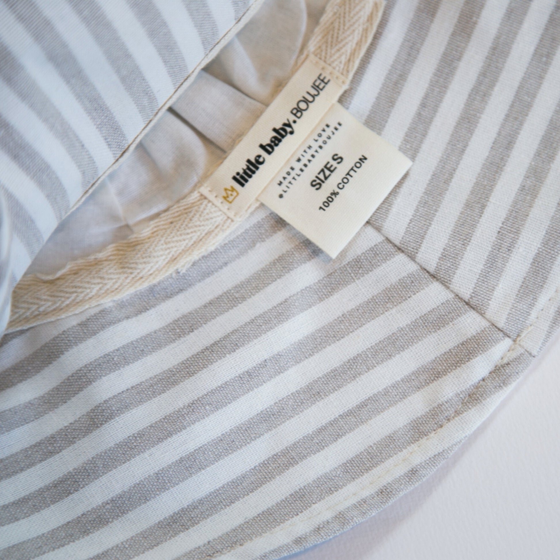 Inside view of Cloudy Stripes grey stripe baby sun hat, showing the soft inner lining and brand tags for comfort and authenticity