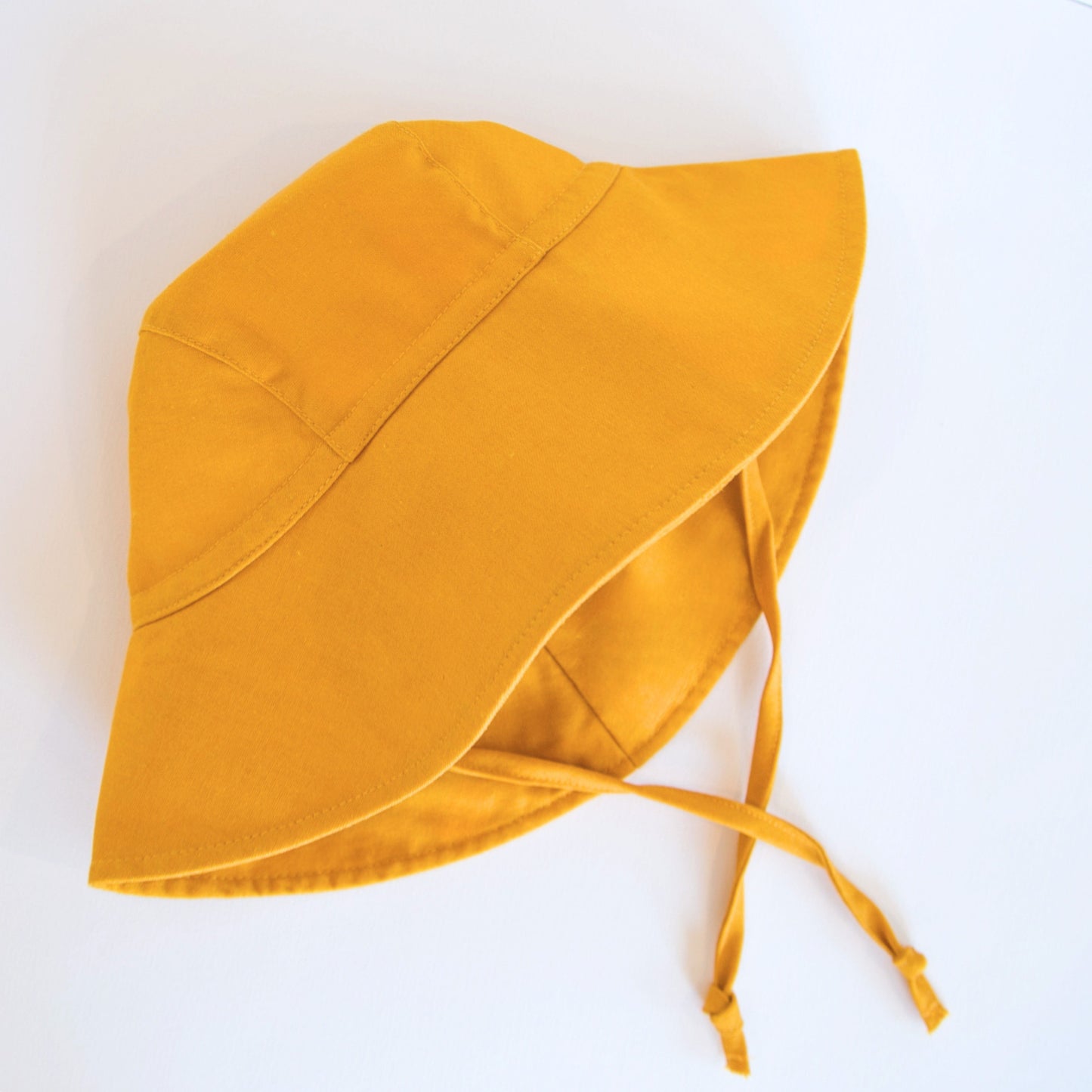 Front view of Golden Glow mustard baby sun hat, showcasing the wide brim and soft breathable cotton fabric