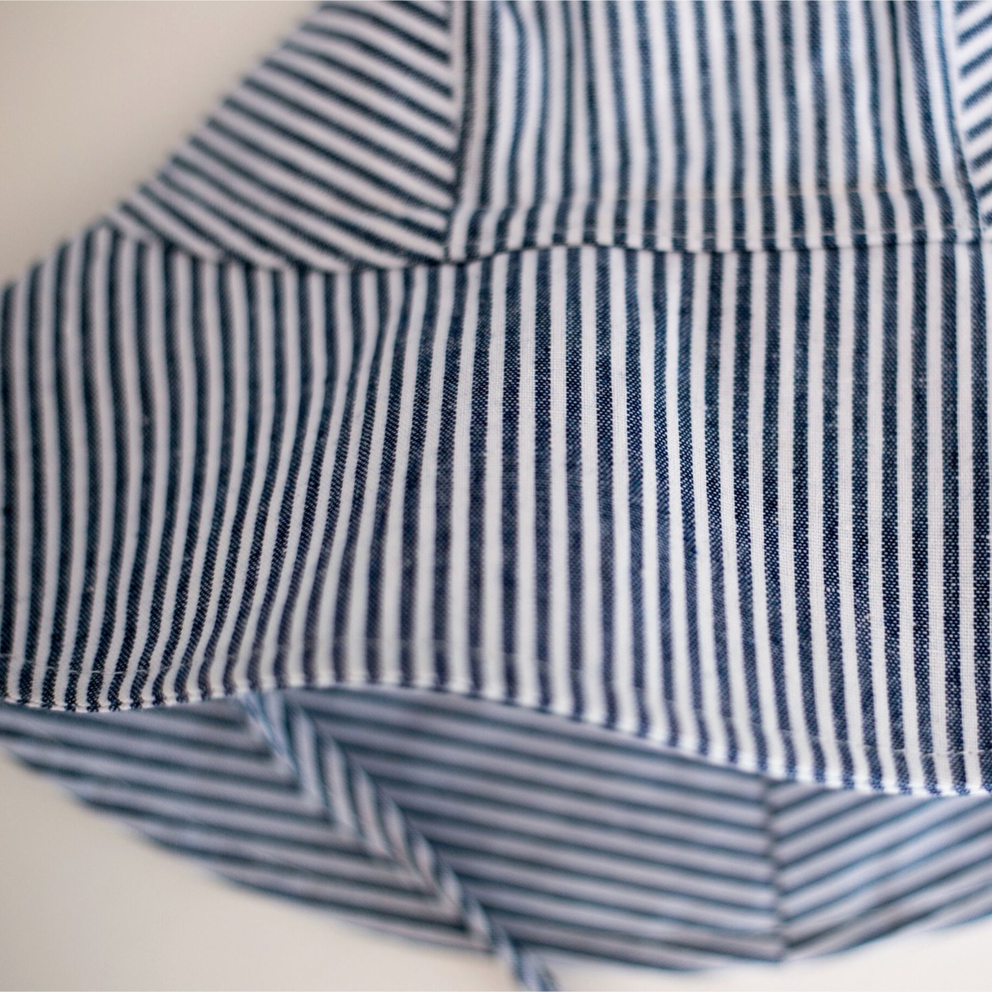Close-up detail shot of Ocean Breeze blue stripe baby sun hat, emphasising the breathable cotton material, stitching, and pattern