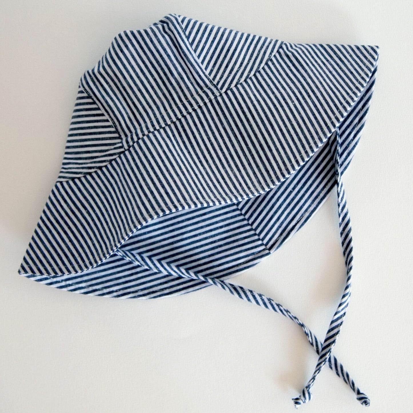 Front view of Ocean Breeze blue stripe baby sun hat, made from breathable cotton with a wide brim and adjustable neck tie