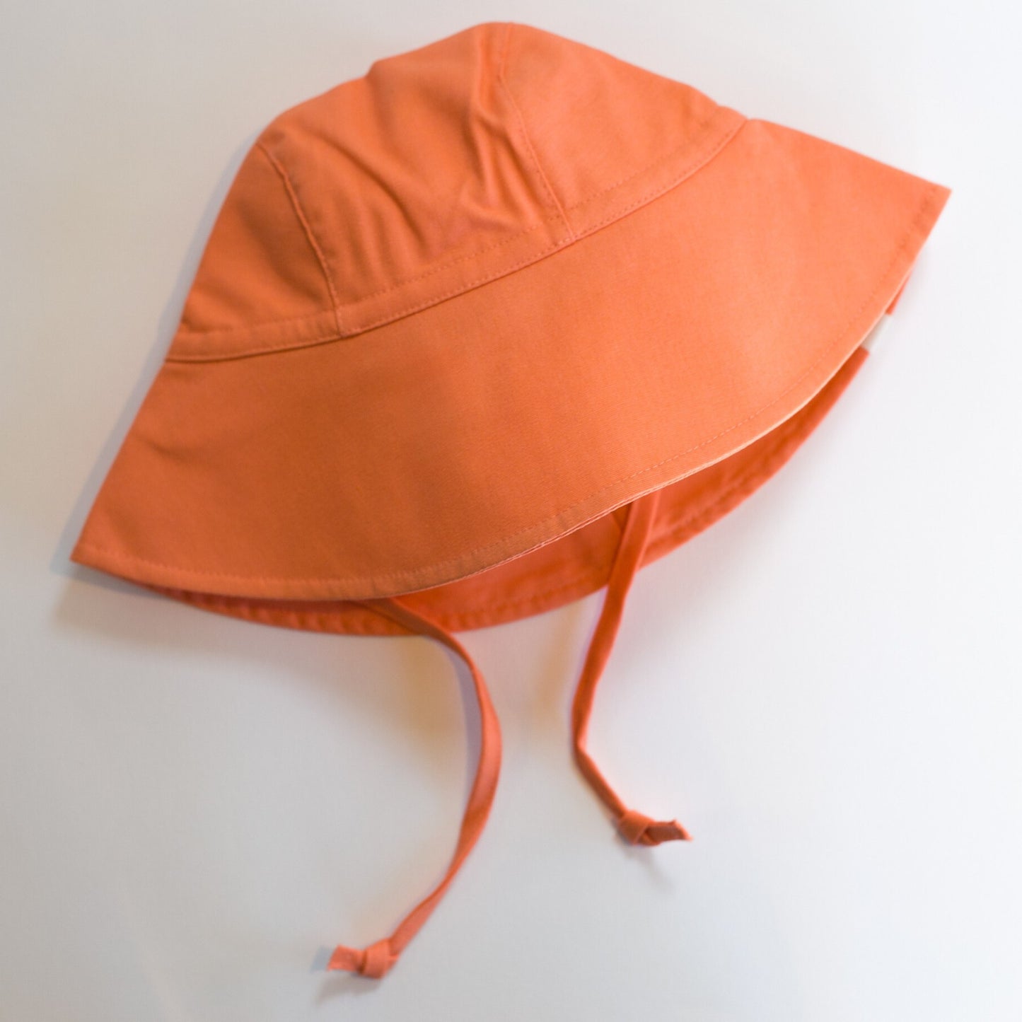 Peaches and Cream peach baby sun hat made from breathable cotton, featuring a wide brim for stylish sun protection