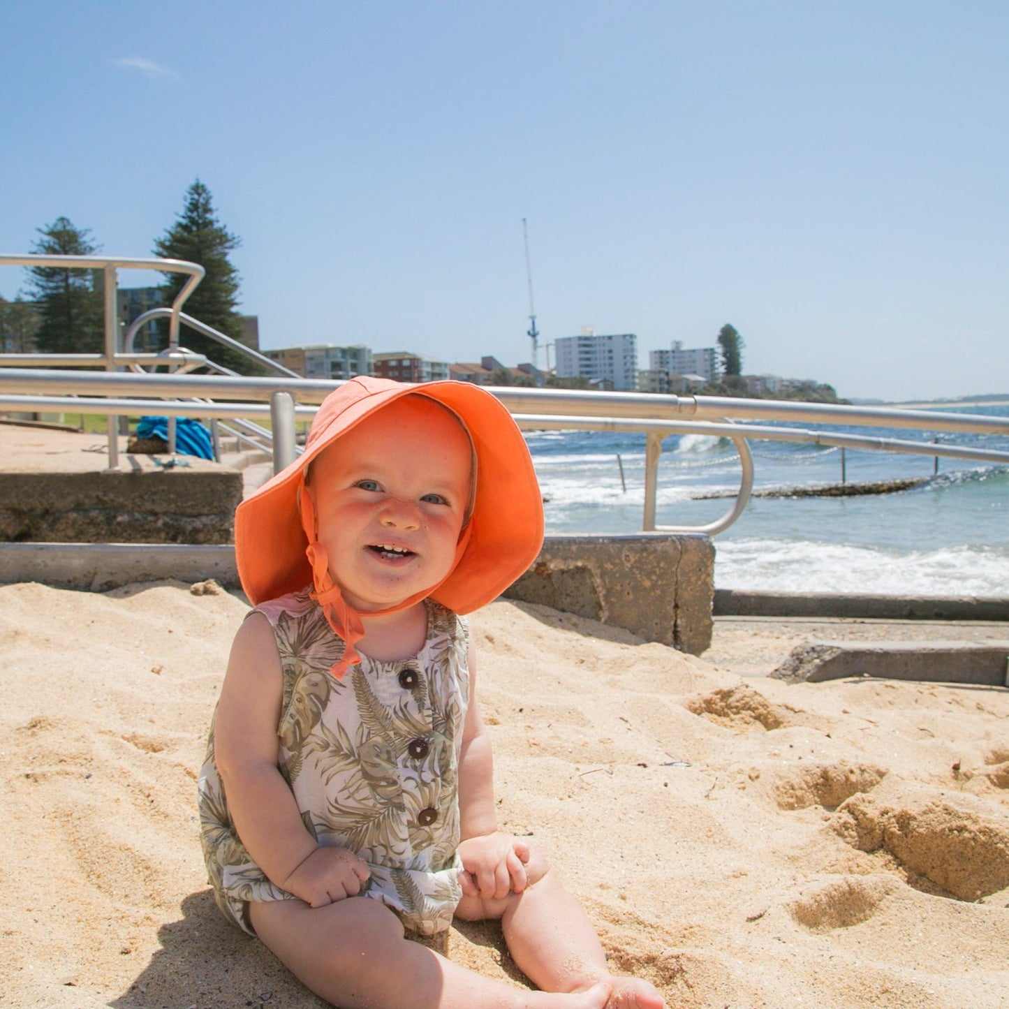 Lifestyle image of a baby wearing Sand Dune beige baby sun hat made from breathable cotton, enjoying outdoor play in the sun