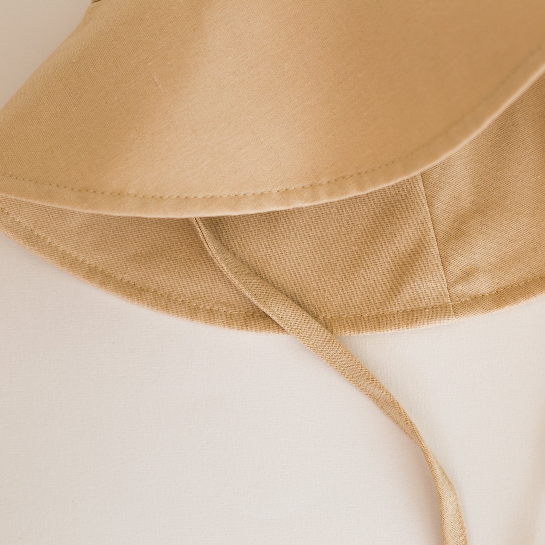 Close-up of Sand Dune beige baby sun hat showcasing breathable cotton fabric and fine stitching details