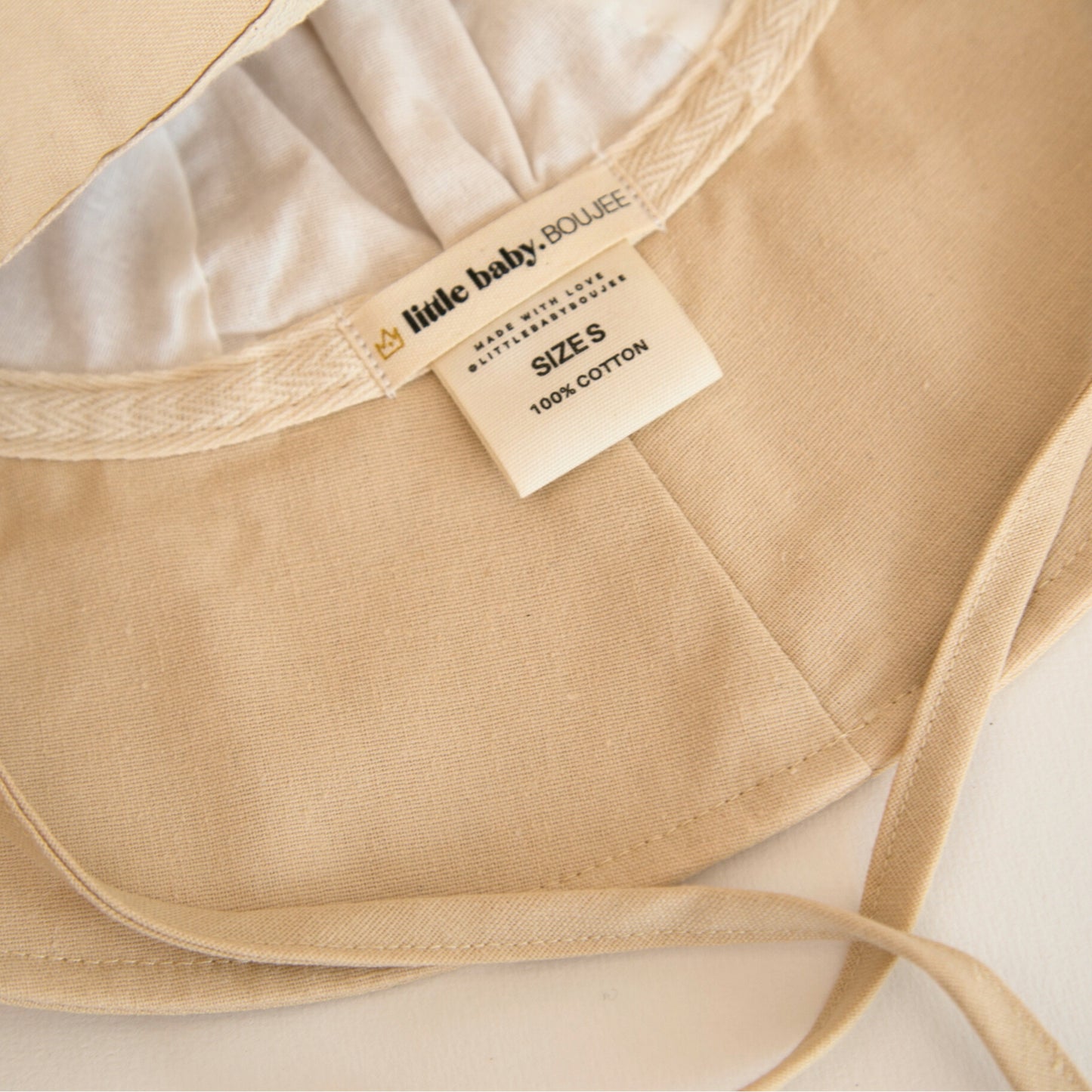 Inside view of Sand Dune beige baby sun hat, showcasing the soft inner lining, breathable cotton fabric, and branding labels for a premium touch