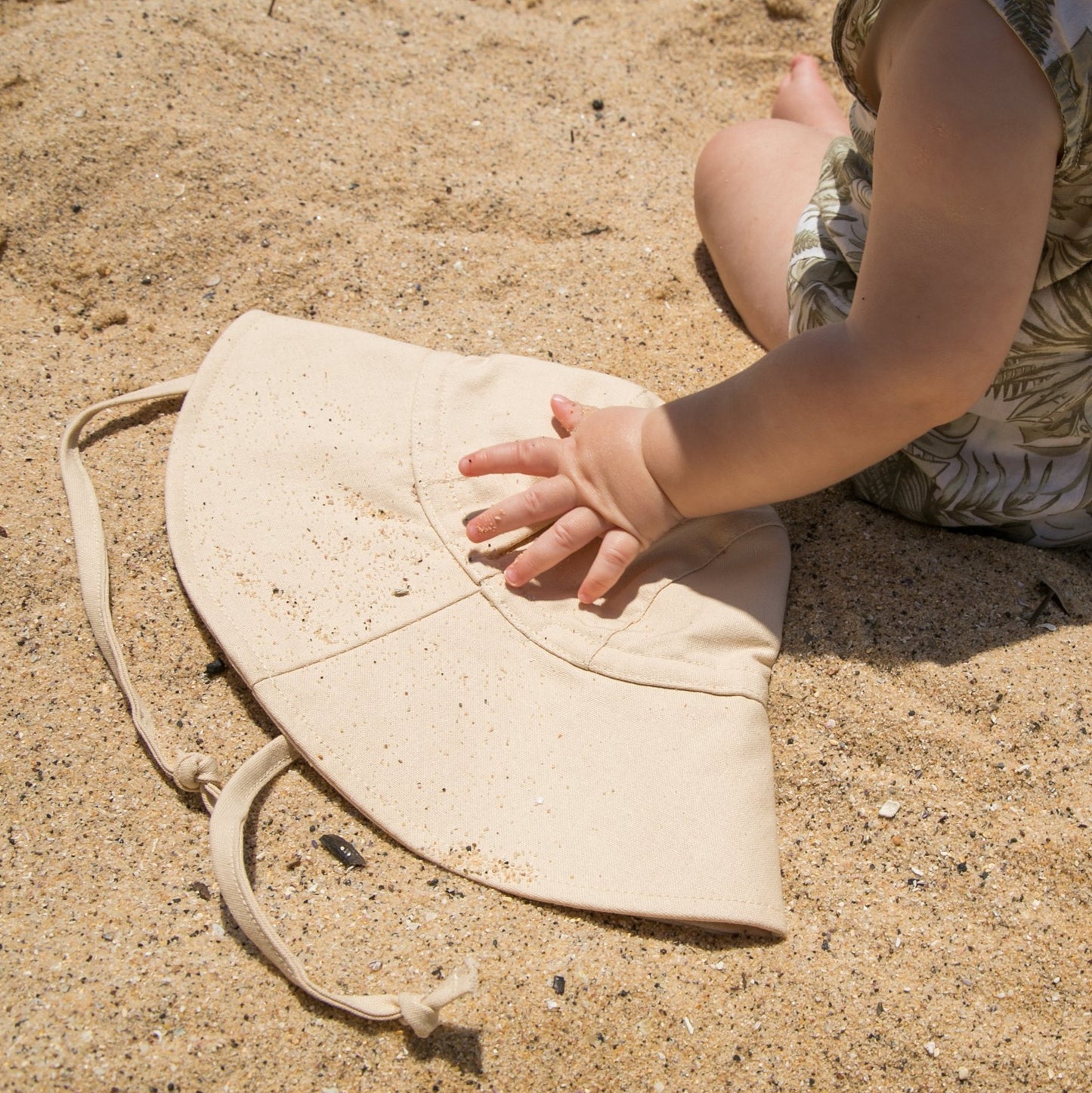 Baby holding Sand Dune beige baby sun hat, made from breathable cotton for all-day comfort and style