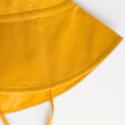 Close-up detail shot of Golden Glow mustard baby sun hat, focusing on the breathable cotton fabric, stitching, and high-quality craftsmanship