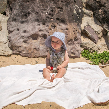 Lifestyle image of a baby wearing the Ocean Breeze blue stripe baby sun hat, enjoying the outdoors in breathable cotton comfort