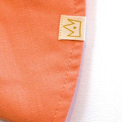 Close-up of Peaches and Cream peach baby sun hat showing breathable cotton and exterior brand tag  